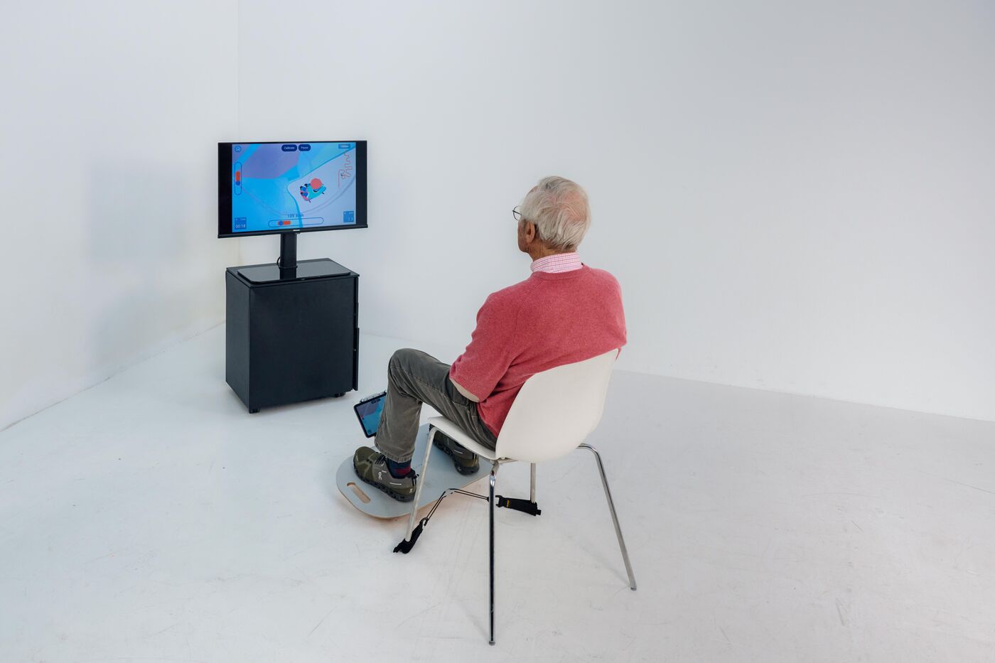 Person training while seated on the ICAROS I.S.T. Board in front of a screen